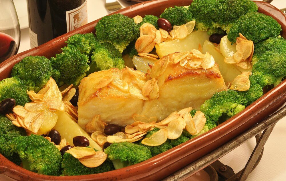 Posta de Bacalhau assada, regada com azeite e alho, batatas assadas, brócolis, azeitonas e arroz.